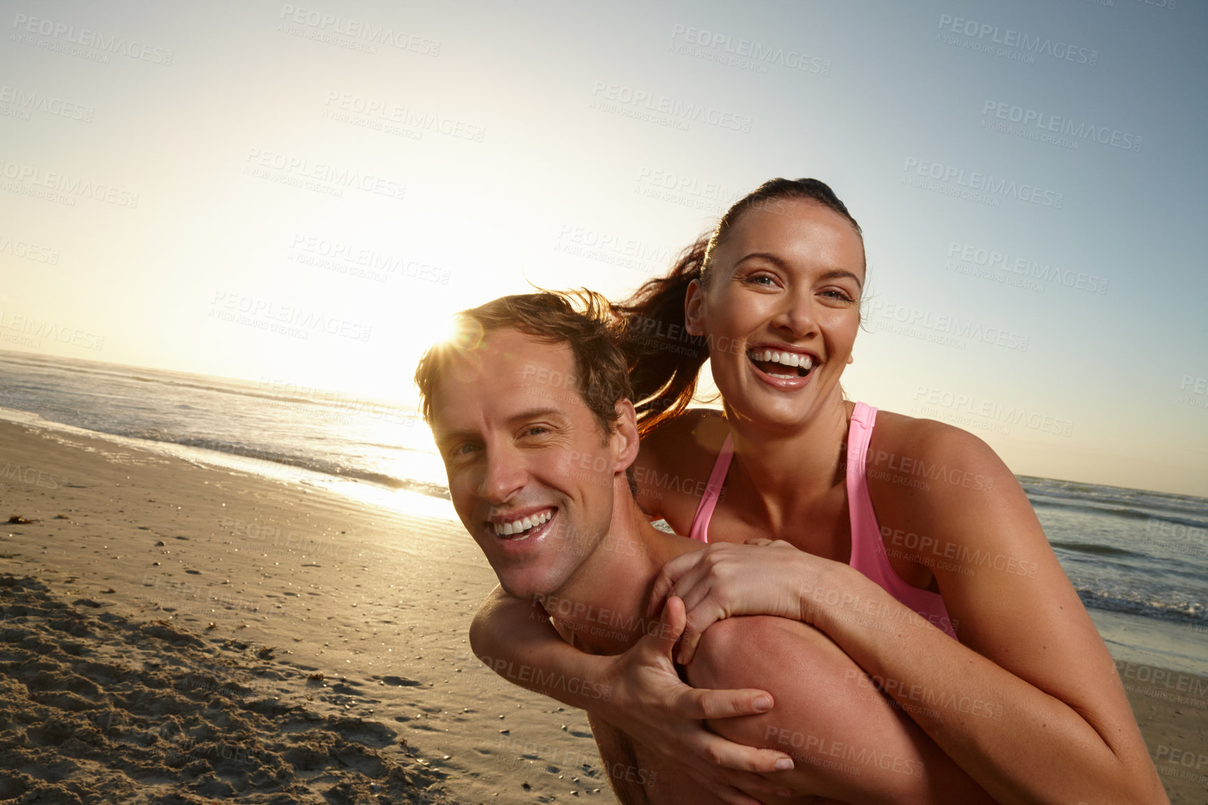 Buy stock photo Portrait of a man giving his girlfriend a piggyback ride at the beach