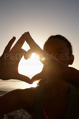 Buy stock photo Shot of a woman making a heart shape with her hands at the beach