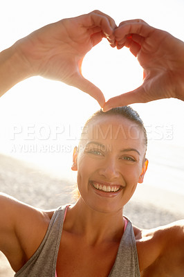 Buy stock photo Portrait of a woman making a heart shape with her hands at the beach