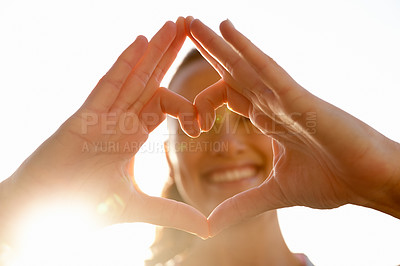 Buy stock photo Closeup shot of a woman making a heart shape with her hands while standing outside