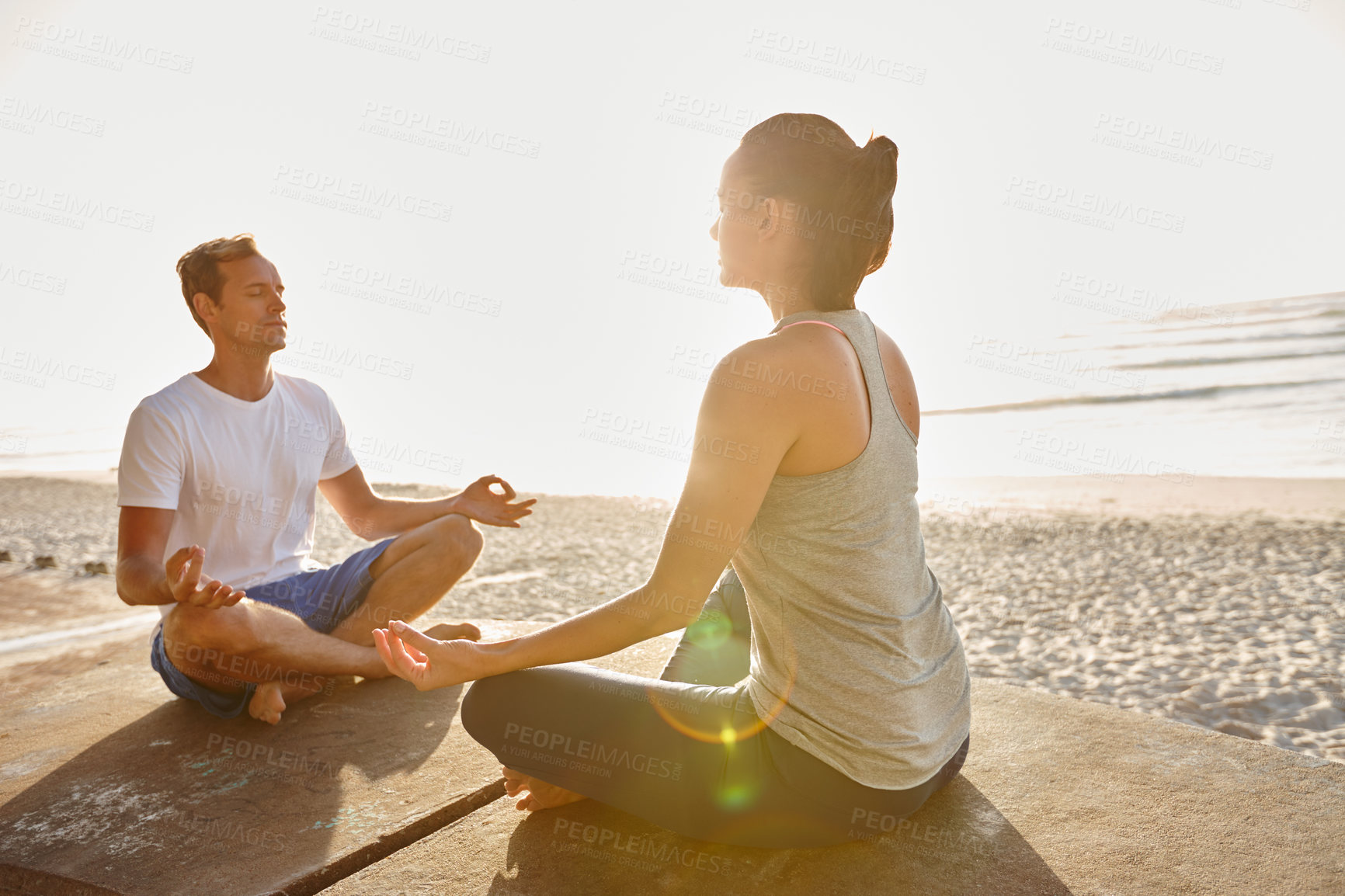 Buy stock photo Shot of a couple meditating together at the beach