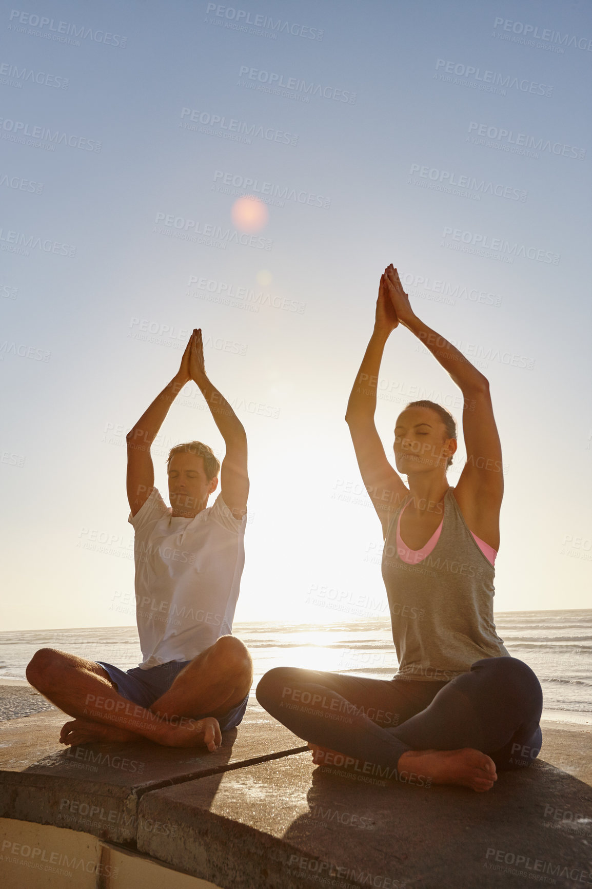 Buy stock photo Shot of a couple doing yoga at the beach at sunset