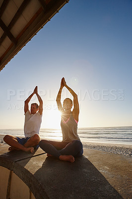 Buy stock photo Shot of a couple doing yoga at the beach at sunset