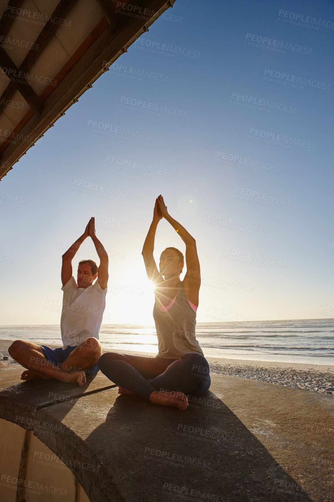 Buy stock photo Shot of a couple doing yoga at the beach at sunset