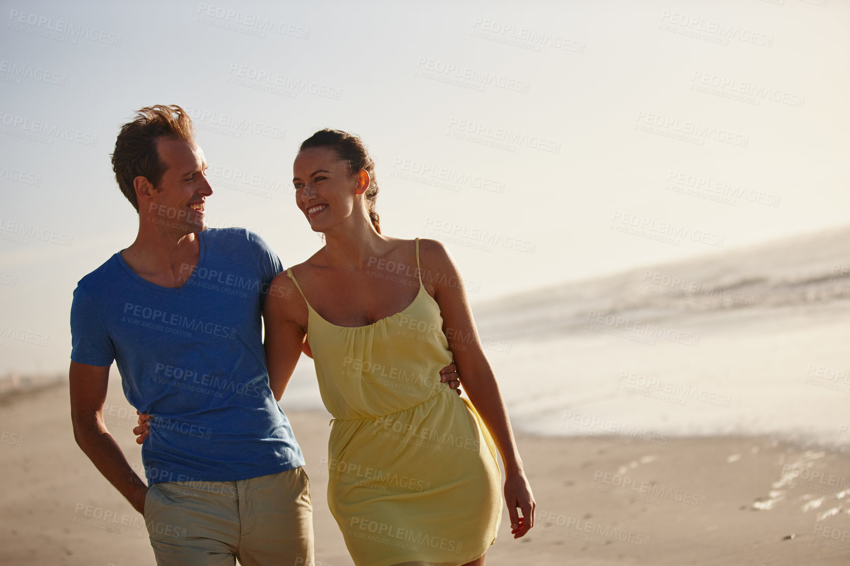 Buy stock photo Shot of an affectionate couple walking on the beach