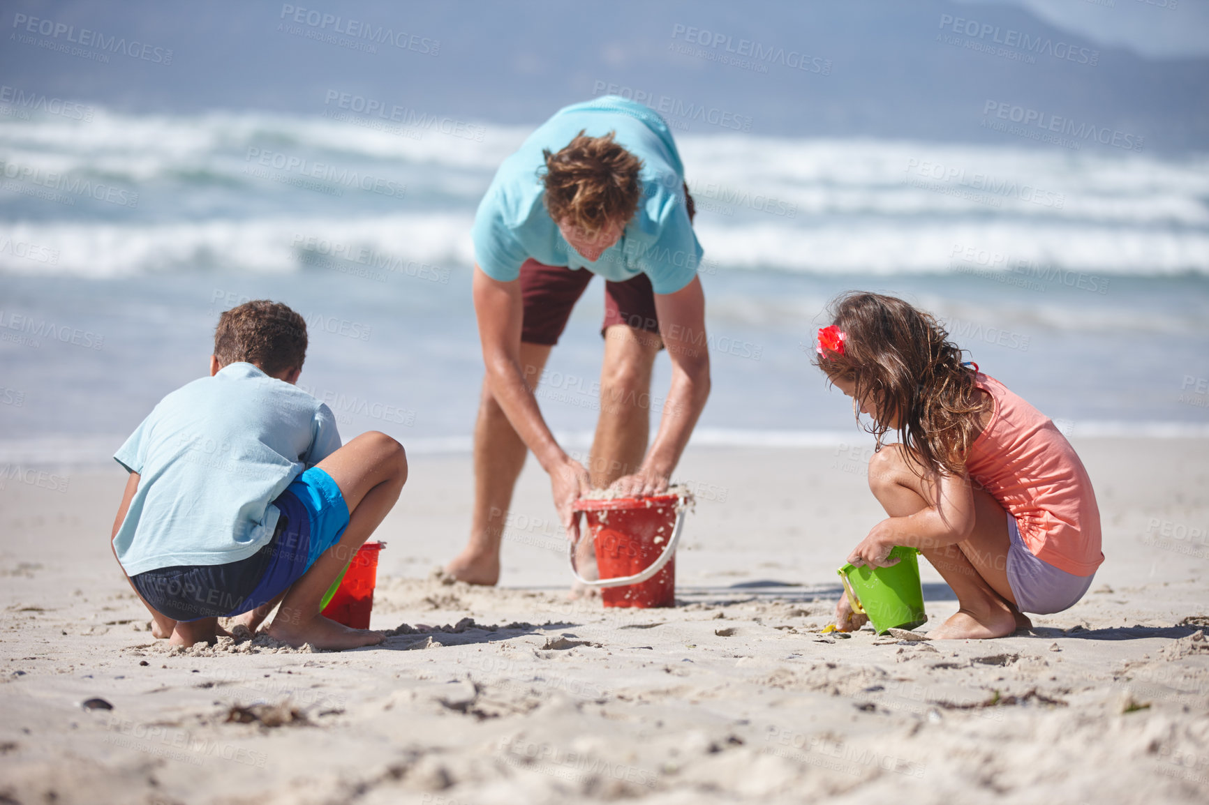 Buy stock photo Shot of a happy family building sandcastles together at the beach