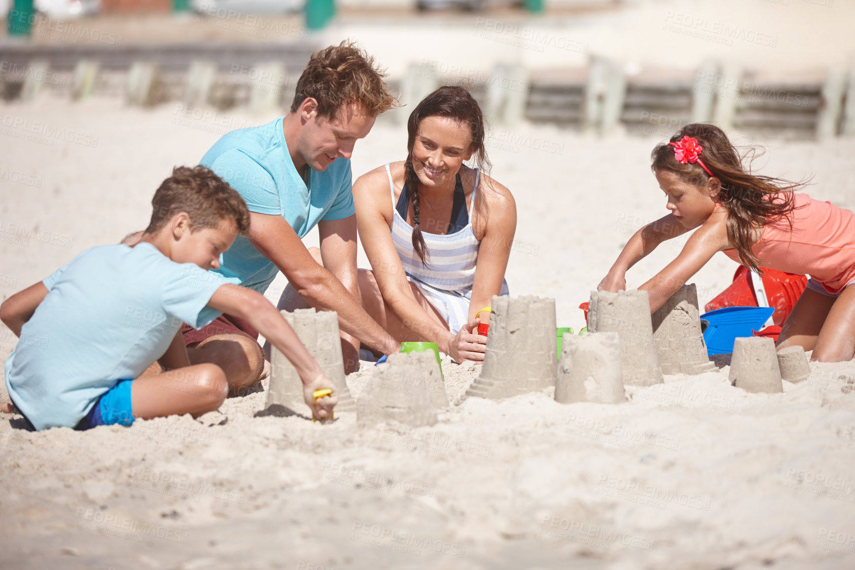 Buy stock photo Shot of a happy family building sandcastles together at the beach