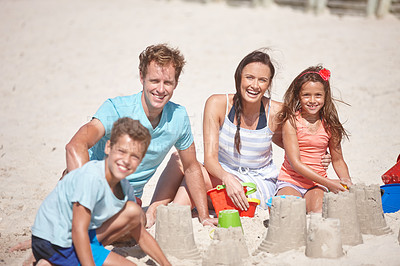 Buy stock photo Shot of a happy family building sandcastles together at the beach