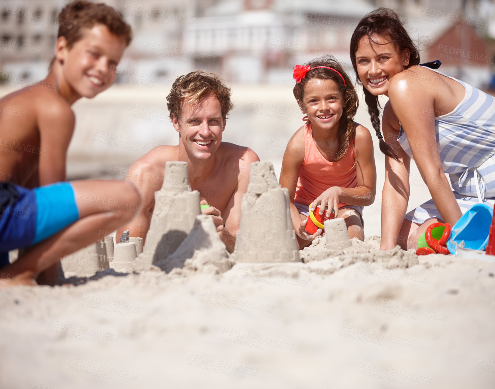 Buy stock photo Sandcastle, help and portrait with family at beach for summer vacation, bonding and game. Support, holiday getaway and toys with parents and children playing with sand outdoor for adventure and trip 