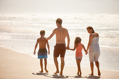 Buy stock photo Rearview shot of a family enjoying a walk along the beach