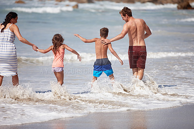 Buy stock photo Shot of a family playing in the waves at the beach