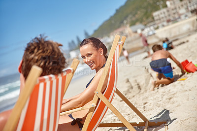 Buy stock photo Shot of a couple sitting on beach chairs while their children play in the background