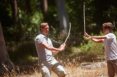Buy stock photo Shot of a young father and son playing with branches on a camping trip