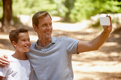 Buy stock photo Shot of a father and son taking a selfie together on a camping trip in the forest