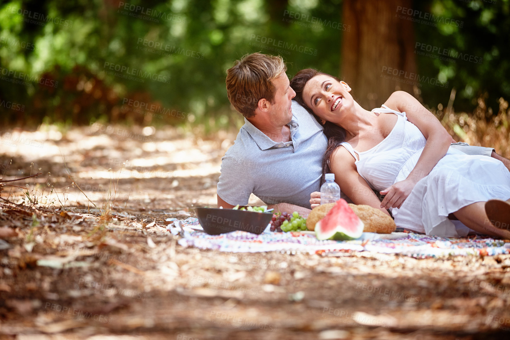 Buy stock photo Shot of an affectionate couple enjoying a picnic in the forest