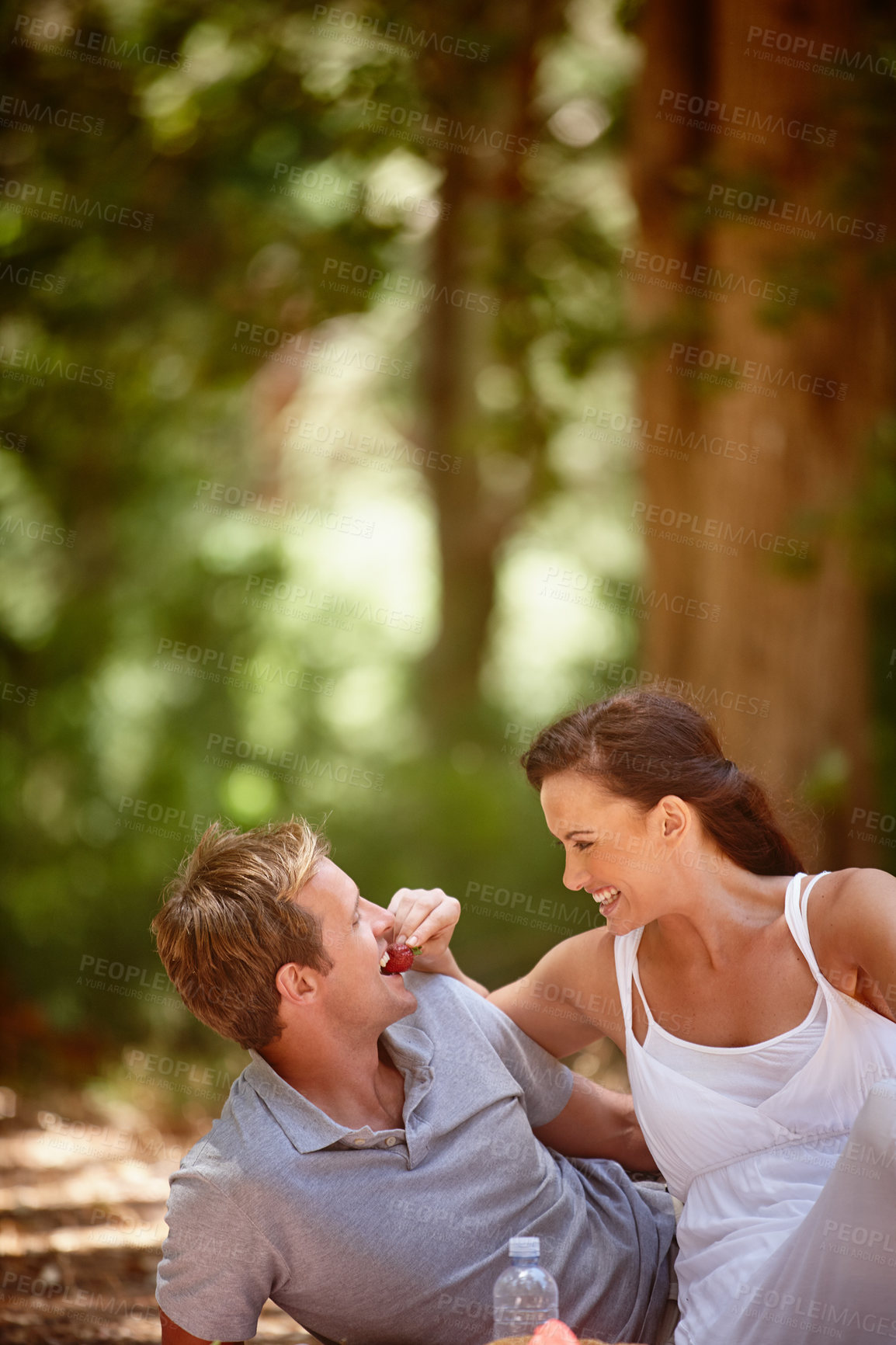 Buy stock photo Shot of an affectionate couple enjoying a picnic in the forest