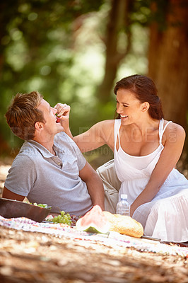 Buy stock photo Shot of an affectionate couple enjoying a picnic in the forest