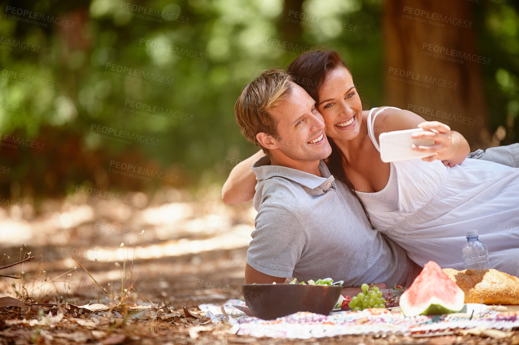 Buy stock photo Shot of an affectionate couple enjoying a picnic in the forest