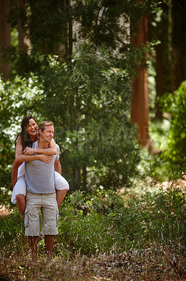 Buy stock photo Shot of a man piggybacking his girlfriend in the forest