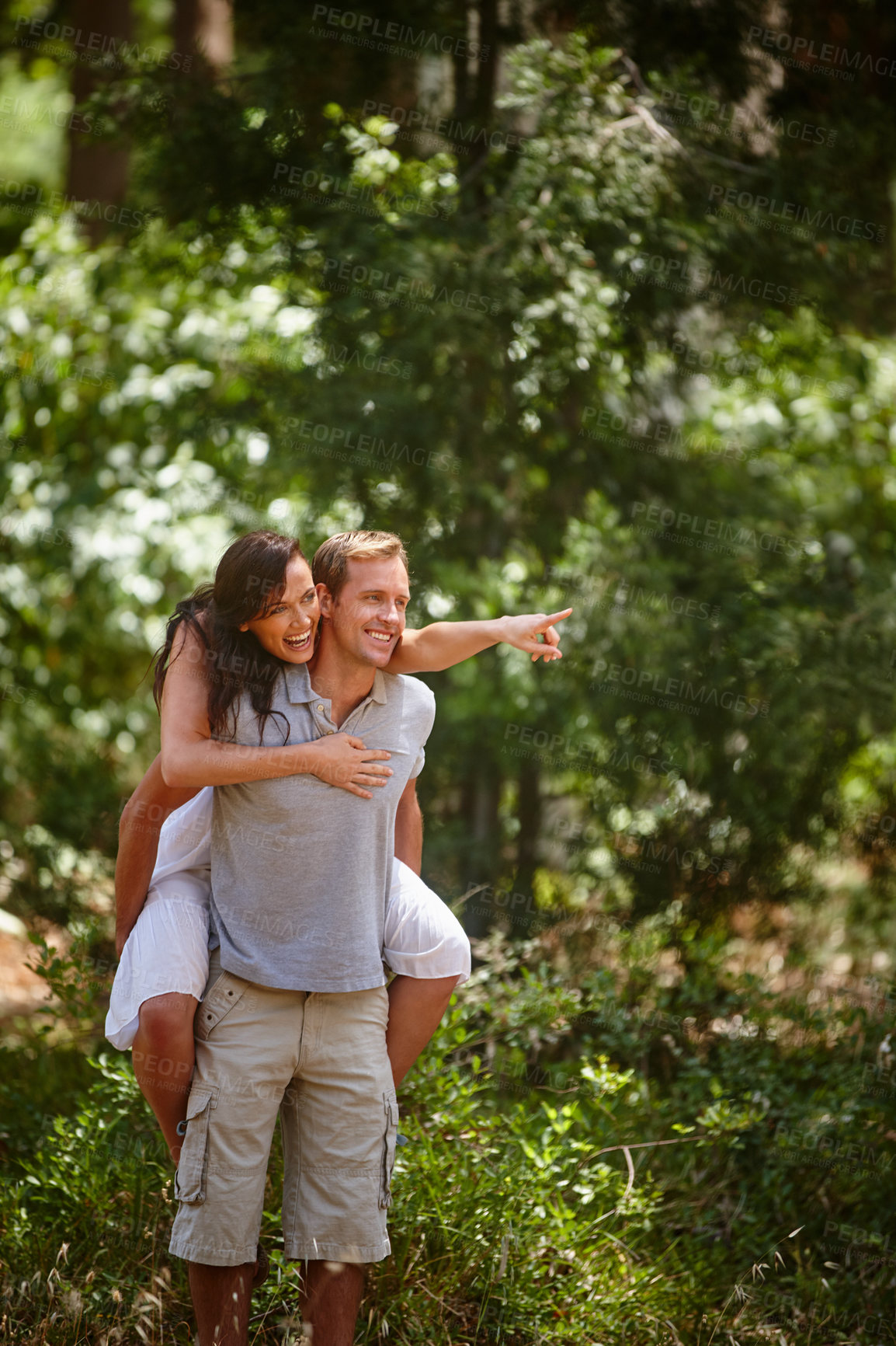 Buy stock photo Shot of a man piggybacking his girlfriend in the forest