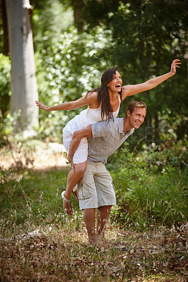 Buy stock photo Shot of a man piggybacking his girlfriend in the forest
