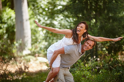 Buy stock photo Shot of a man piggybacking his girlfriend in the forest