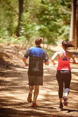 Buy stock photo Rearview shot of a couple jogging in the forest