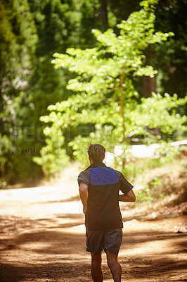 Buy stock photo Rearview shot of a man jogging in a forrest