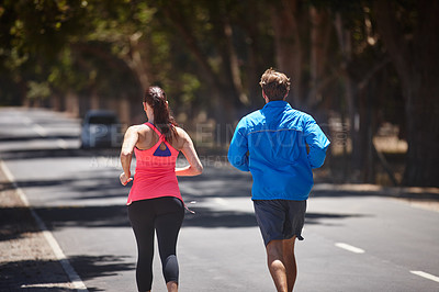 Buy stock photo Rearview shot of a couple jogging on a road