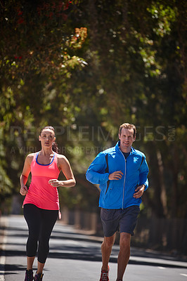 Buy stock photo Cropped shot of a couple jogging on a road
