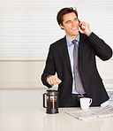 Young business man using cellphone while preparing coffee
