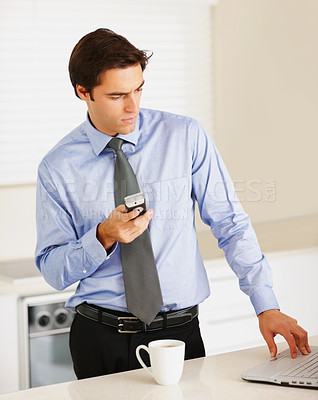 Buy stock photo Businessman, phone and laptop with coffee in kitchen for email, research or networking for morning routine. Entrepreneur, person or serious with cup for espresso or cappuccino with technology at home