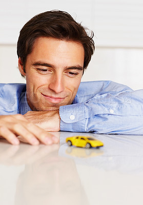 Buy stock photo Toy car, business and man with a smile, office and employee with happiness, cheerful or entrepreneur. Person, agent or consultant playing with vehicle, break or relax with peace, professional or calm