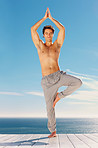 Sexy young man meditating on a porch by the sea