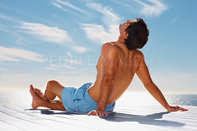 Buy stock photo Sea, relax and shirtless man on a pier with a view of the water in summer while on holiday or vacation. Freedom, ocean or sky and the body of a young tourist tanning outdoor on a deck with space