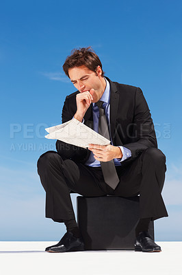 Buy stock photo Yawn, newspaper and businessman reading information sitting by the outdoor blue sky with burn out. Tired, exhausted and sleepy professional young male person in a suit sitting with magazine report.