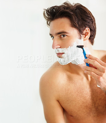 Buy stock photo Skincare, shaving and razor with a man in the bathroom of his home for grooming or morning routine. Face, beauty and foam with a young person in his apartment to shave his beard for hair removal