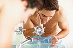 Happy handsome man washing his face at the sink