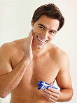 Smiling young guy applying shaving cream from the tube