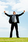 Celebration - Happy business man with his arms outstretched on a field