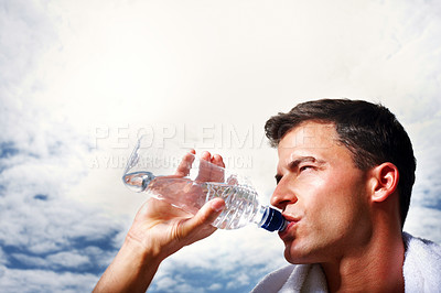 Buy stock photo Closeup of a smart young guy drinking water from the bottle against sky
