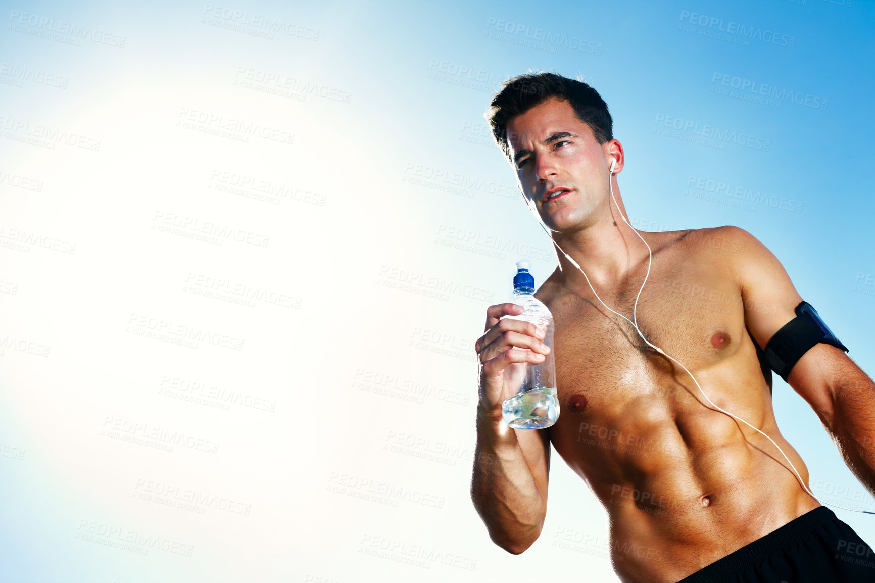 Buy stock photo Water, tired and man on field for workout, earphones and portrait with bottle and summer. Training, cardio and exercise for male person or athlete, running or park for fitness with music and sunlight