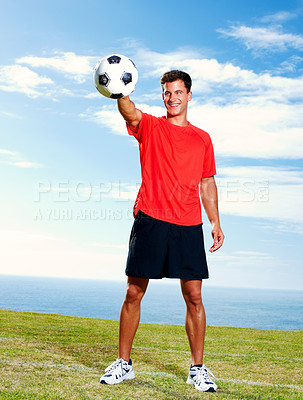 Buy stock photo Happy male soccer player standing with a football on field against the sky
