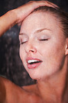 Closeup of a female enjoying a shower against a dark background