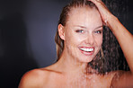 Happy female taking a shower against a dark background