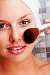 Closeup of a cute female applying make up to face after a bath