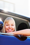 Happy blond woman sitting at the window seat of a car