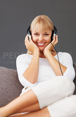 Buy stock photo Happy young woman sitting on couch and listening to music