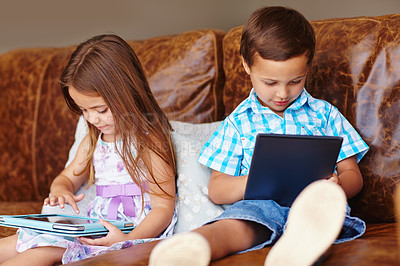 Buy stock photo Shot of a brother and sister using a digital tablet at home