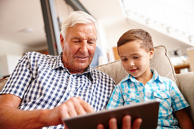Buy stock photo Shot of a little boy and his grandfather using a digital tablet at home